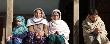 Hajra Bibi with her children sitting in the veranda of her home.